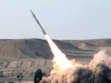 "A ballistic missile launching into the sky from a desert terrain with thick smoke clouds, representing Iran's missile capabilities."